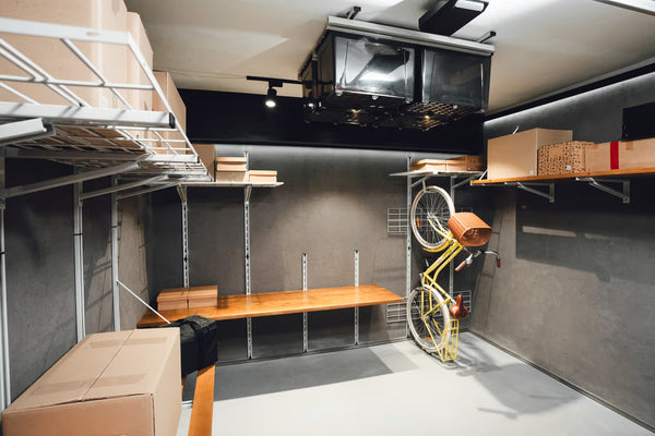 Storage room with shelves, boxes, and a bicycle against a wall.