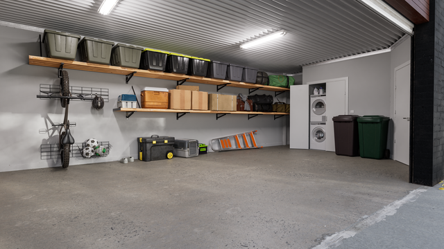 Garage interior with storage shelves, boxes, and a washing machine.
