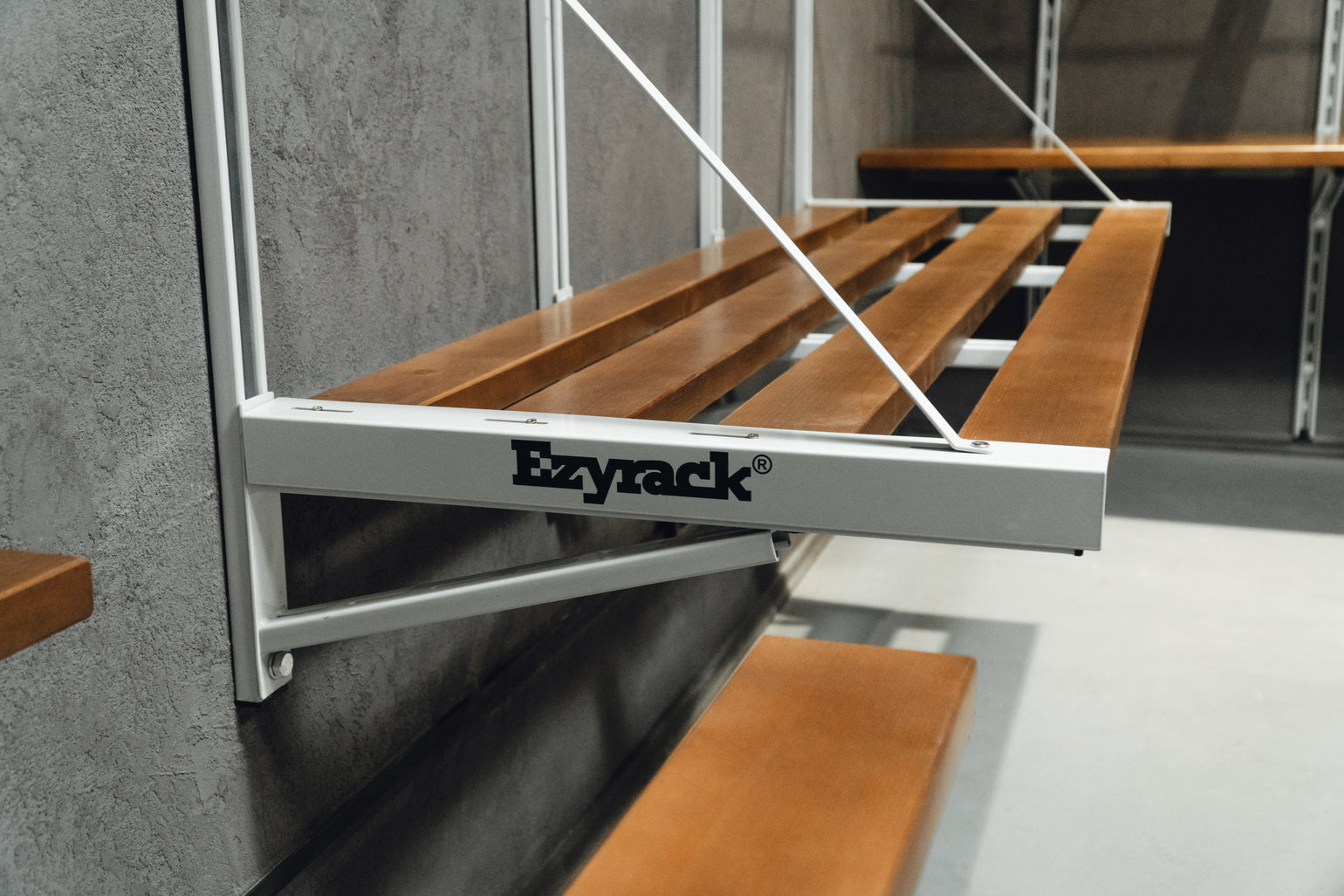 Ezyrack folding shelf with wooden slats against a concrete wall.