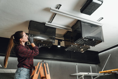 Person installing or adjusting an exhaust hood above a stove.