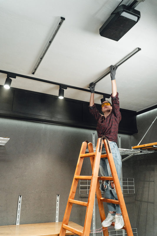 Person on a ladder installing or adjusting ceiling lights in a modern indoor setting.