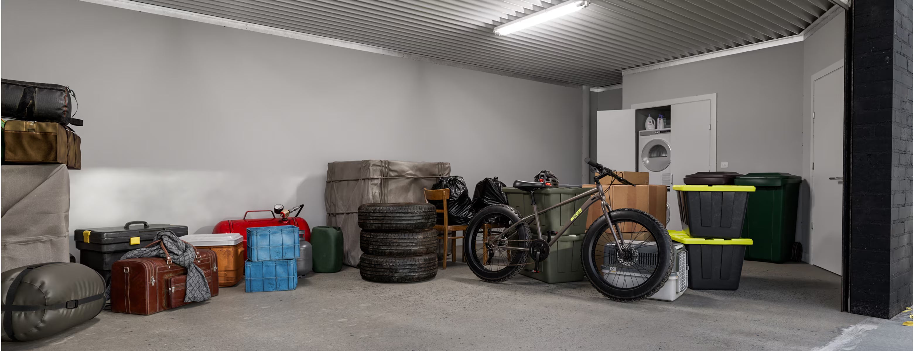 Garage with various items including a motorcycle, storage boxes, and tires.
