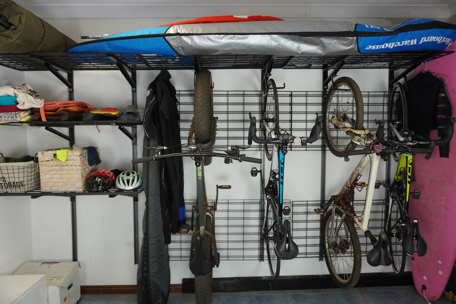 Garage storage system with bikes, kayaks, and other items on shelves and hooks.