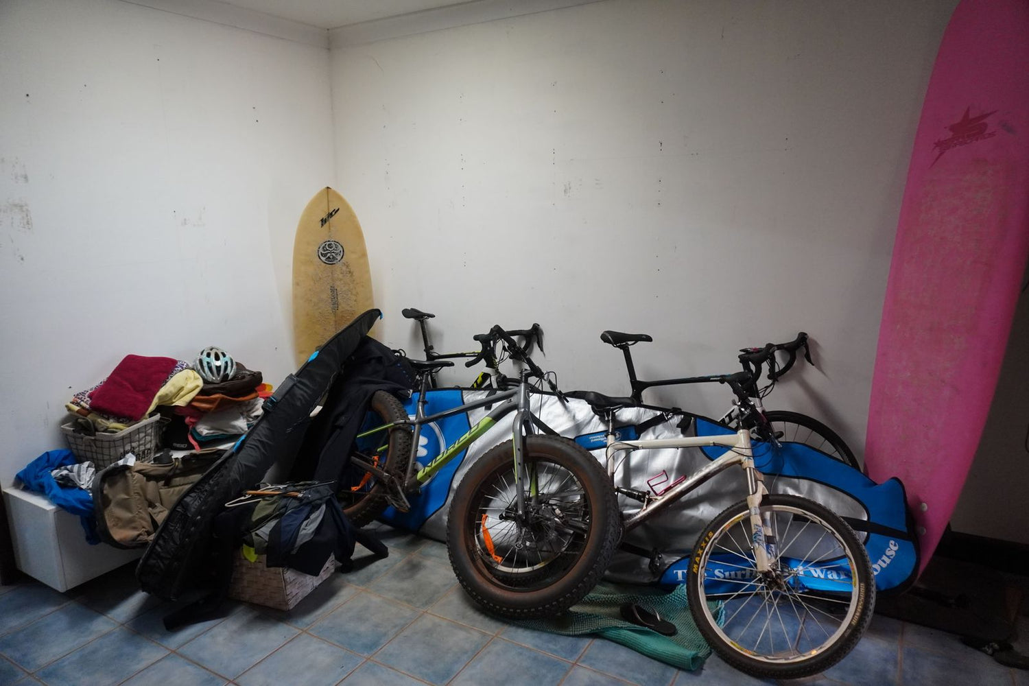 Bicycles and surfboards in a room with a tiled floor