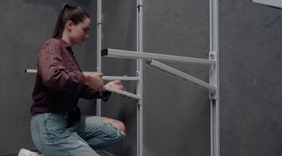 Person working on a metal frame against a gray background