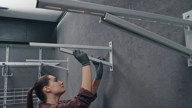Image showing the sixth step of installation, with a person sliding a metal channel into place onto pre-mounted wall brackets.