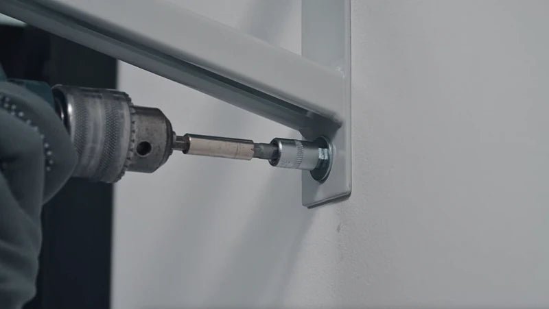 Close-up of a power tool tightening a bolt through the mounting hole of a grey Ezyrack wall channel.
